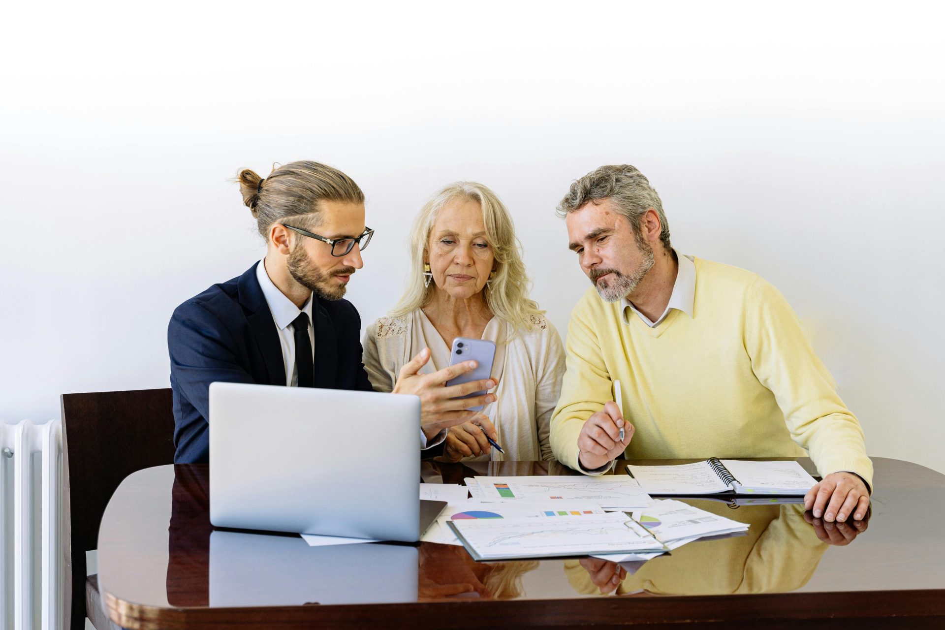 Drei Personen arbeiten während einer Geschäftsbesprechung gemeinsam an Finanzdokumenten.