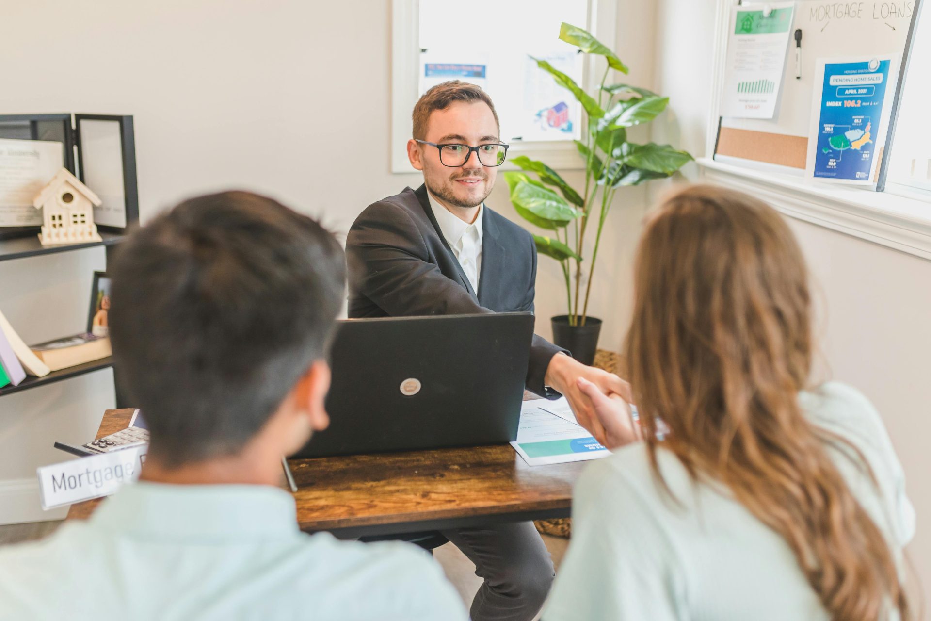 Ein Hypothekenmakler trifft sich in einem Büro mit Kunden und bespricht Verträge und Darlehen.